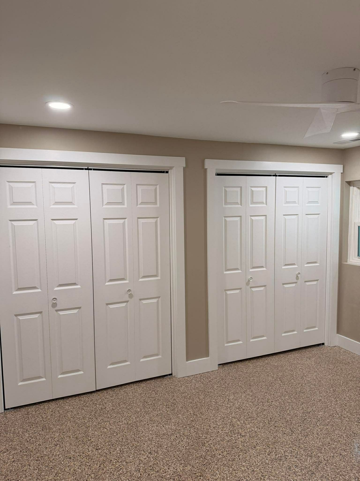 Basement hallway with two white double closet doors and beige walls