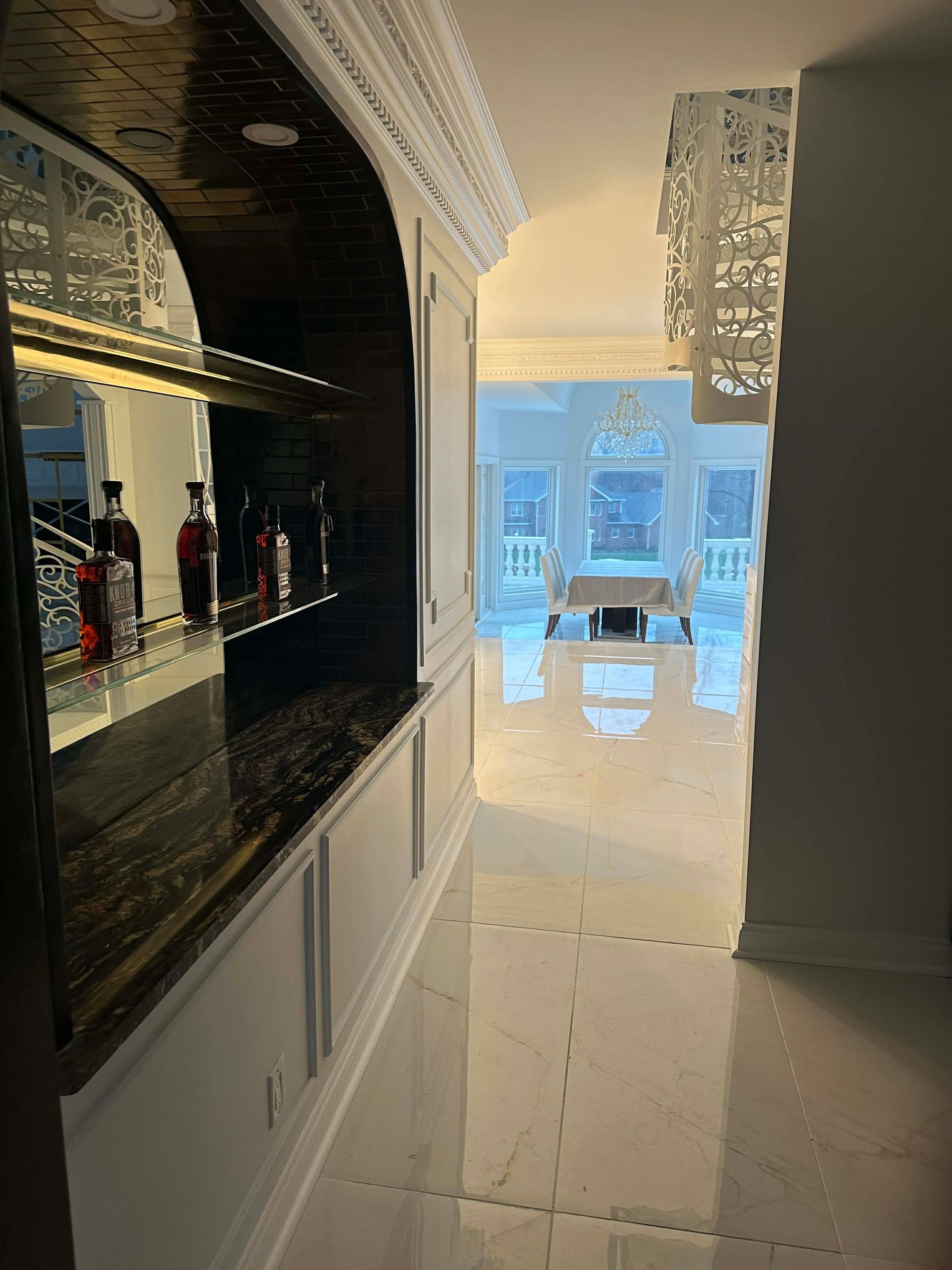 Modern kitchen hallway with glossy black cabinets and a bright living area beyond.