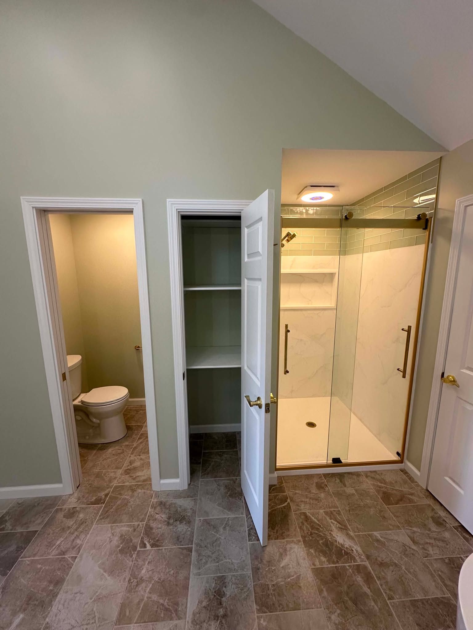 Bathroom with open closet, toilet room, and glass-enclosed shower under a sloped ceiling.