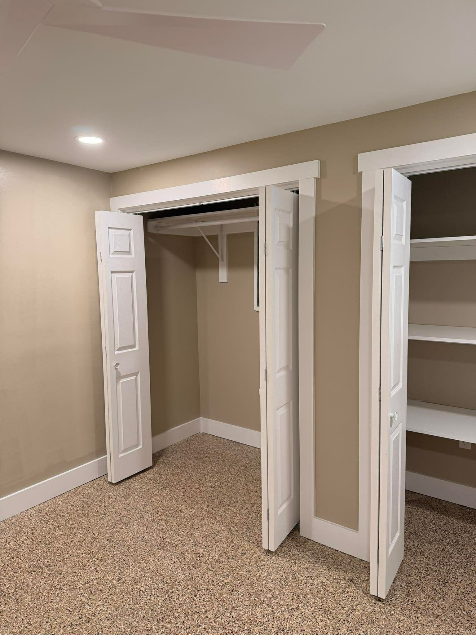 Bedroom with open closet doors, beige walls, and carpeted floor.