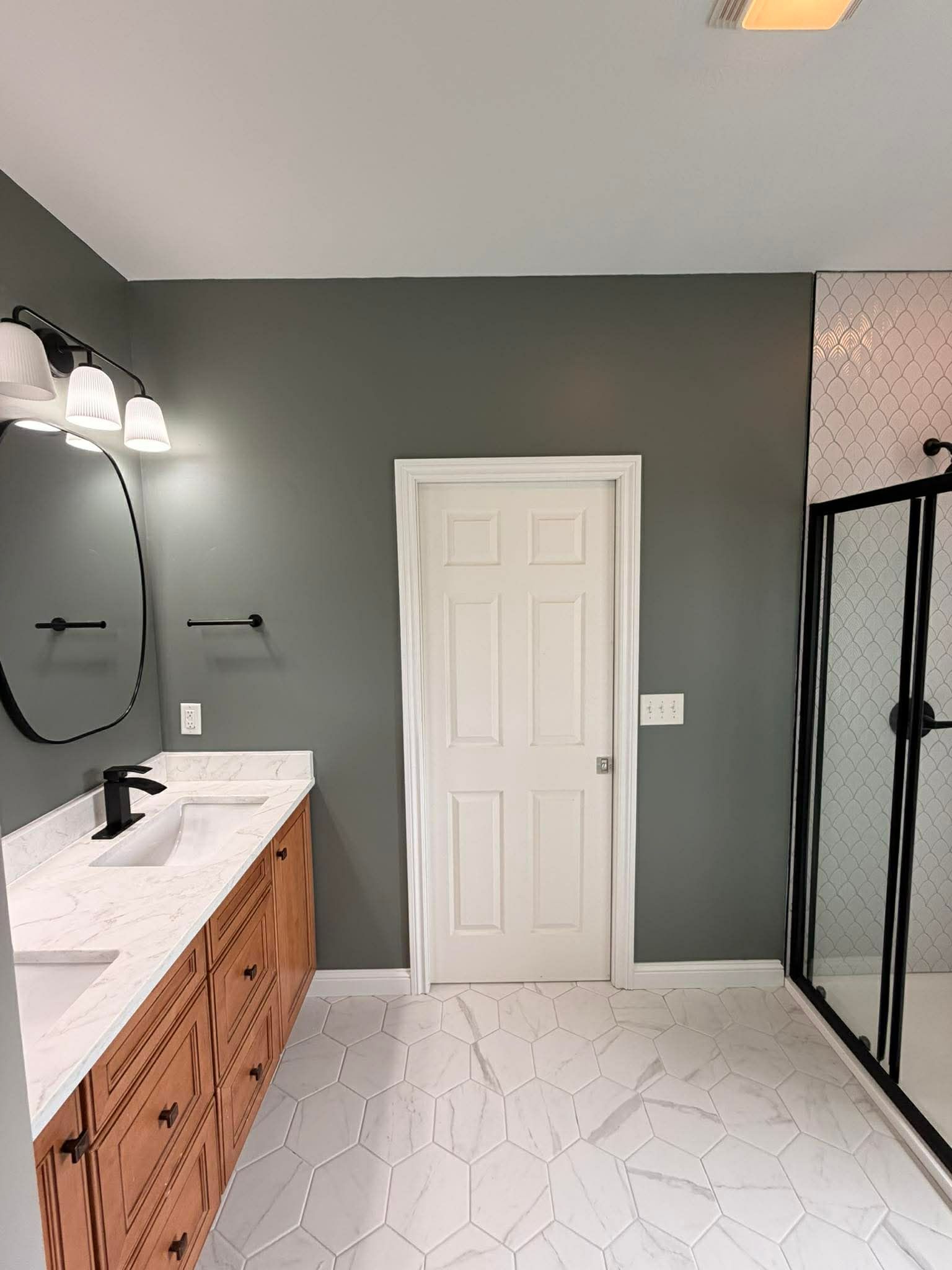 Modern bathroom with gray walls, white vanity and door, black fixtures, and glass shower enclosure