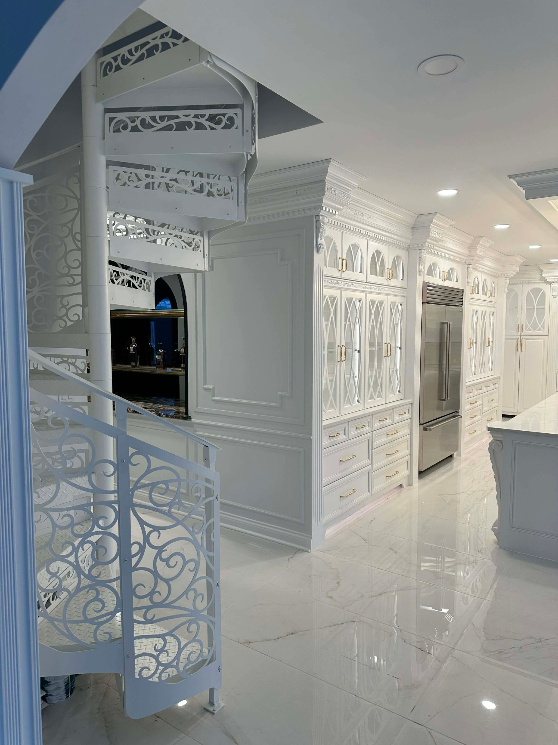 White ornate hallway with decorative walls, curved stairs, and a glossy floor in a bright interior