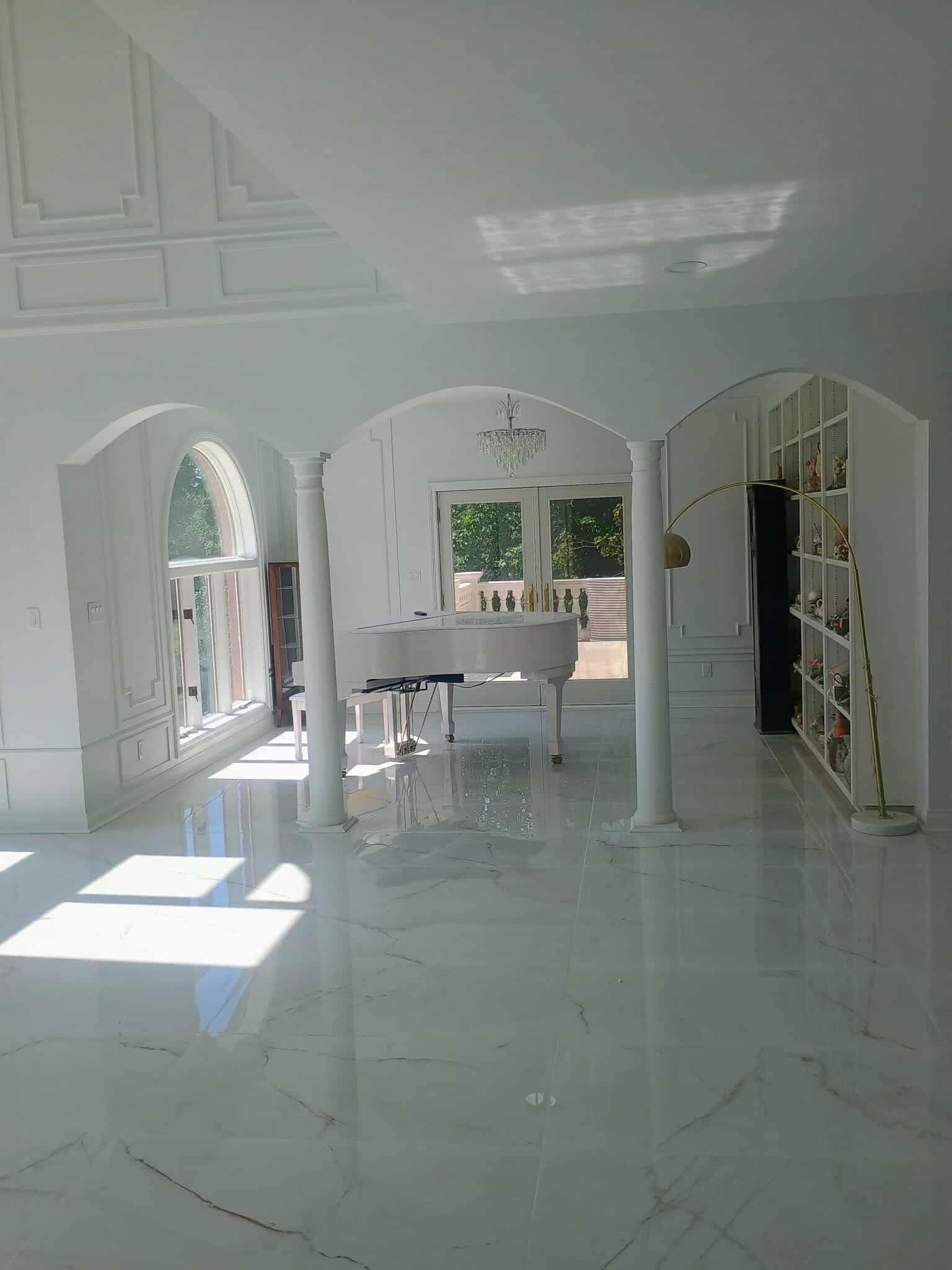Bright white tiled room with arched doorways, built-in shelves, and sunlight streaming across the floor.