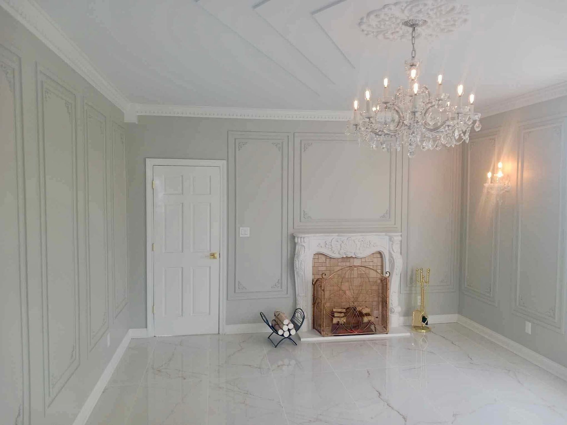 Elegant empty room with pale green walls, chandelier, white fireplace, and glossy white floor.