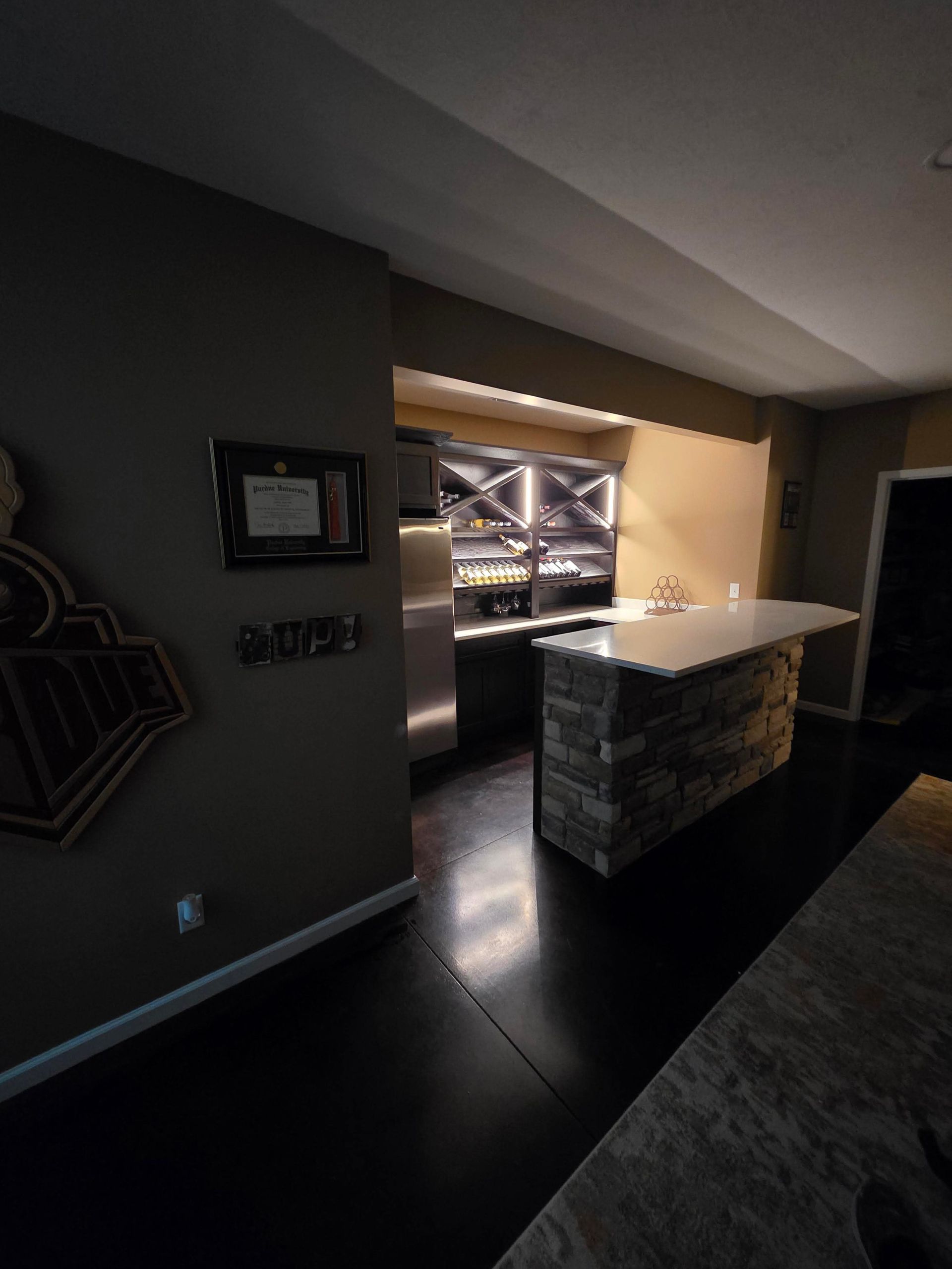 Dim home interior with a stone kitchen island and open pass-through to a bright room.