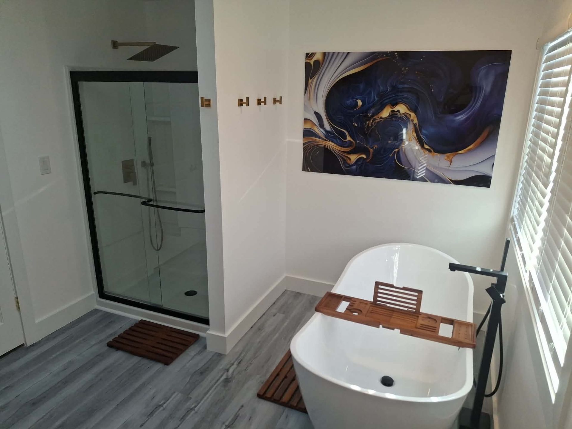 Modern bathroom with glass shower, freestanding tub, and abstract wall art
