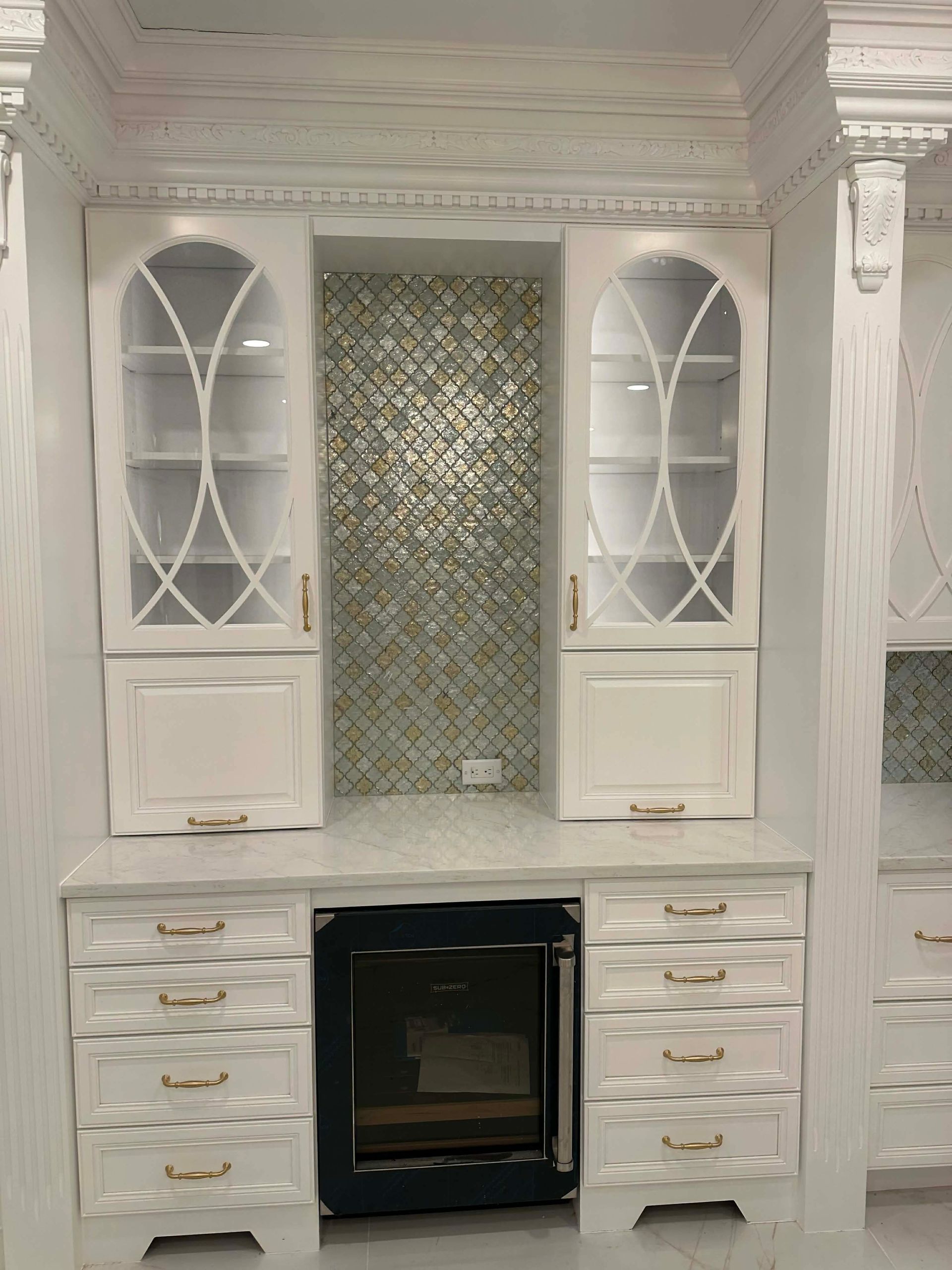 White built-in kitchen cabinets with glass doors, drawers, and a black oven centered below.