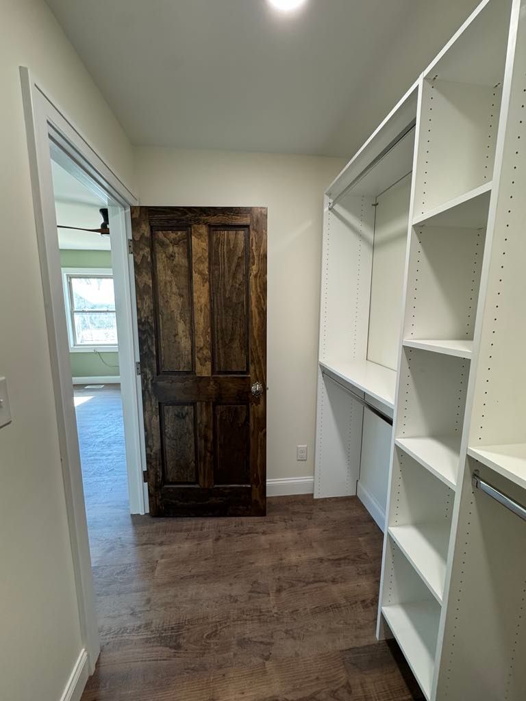Narrow hallway with white built-in shelves and a dark wooden cabinet at the far end