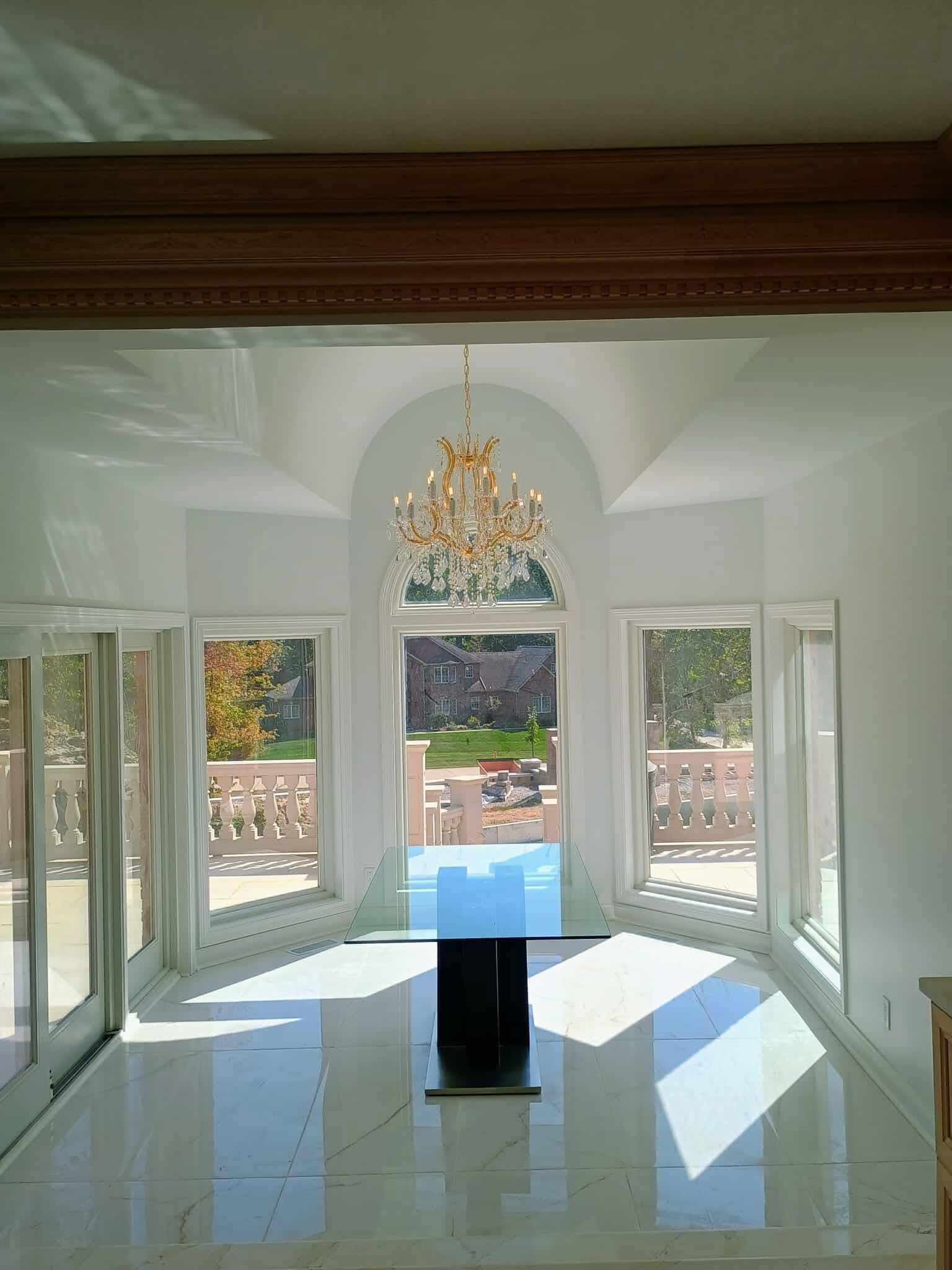 Bright white room with altar, chandelier, large windows, and sunlight on tiled floor