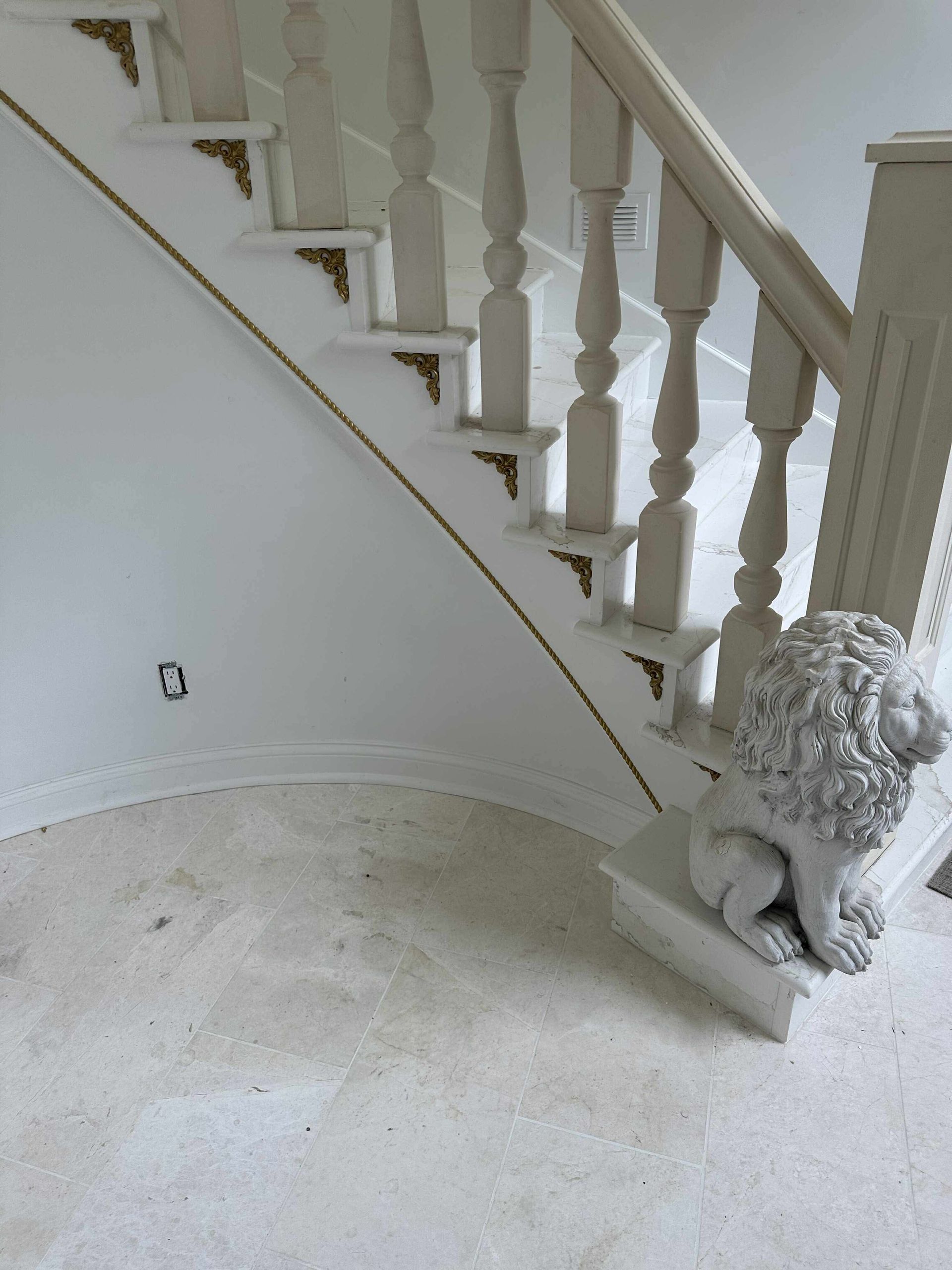 White curved staircase with ornate balusters and a decorative lion statue at the bottom.