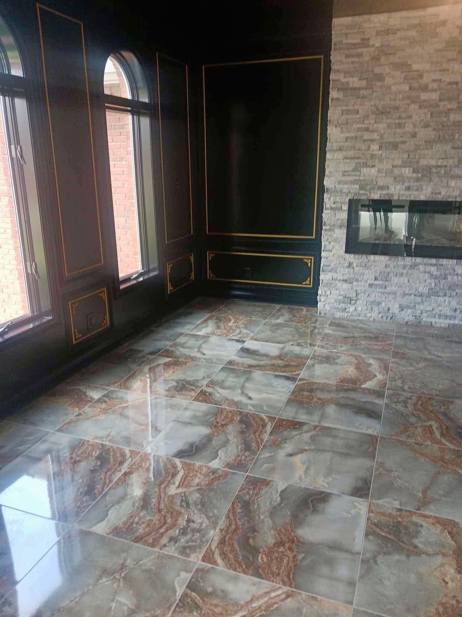 Empty room with glossy marble floor, dark paneled walls, arched window, and exposed brick wall