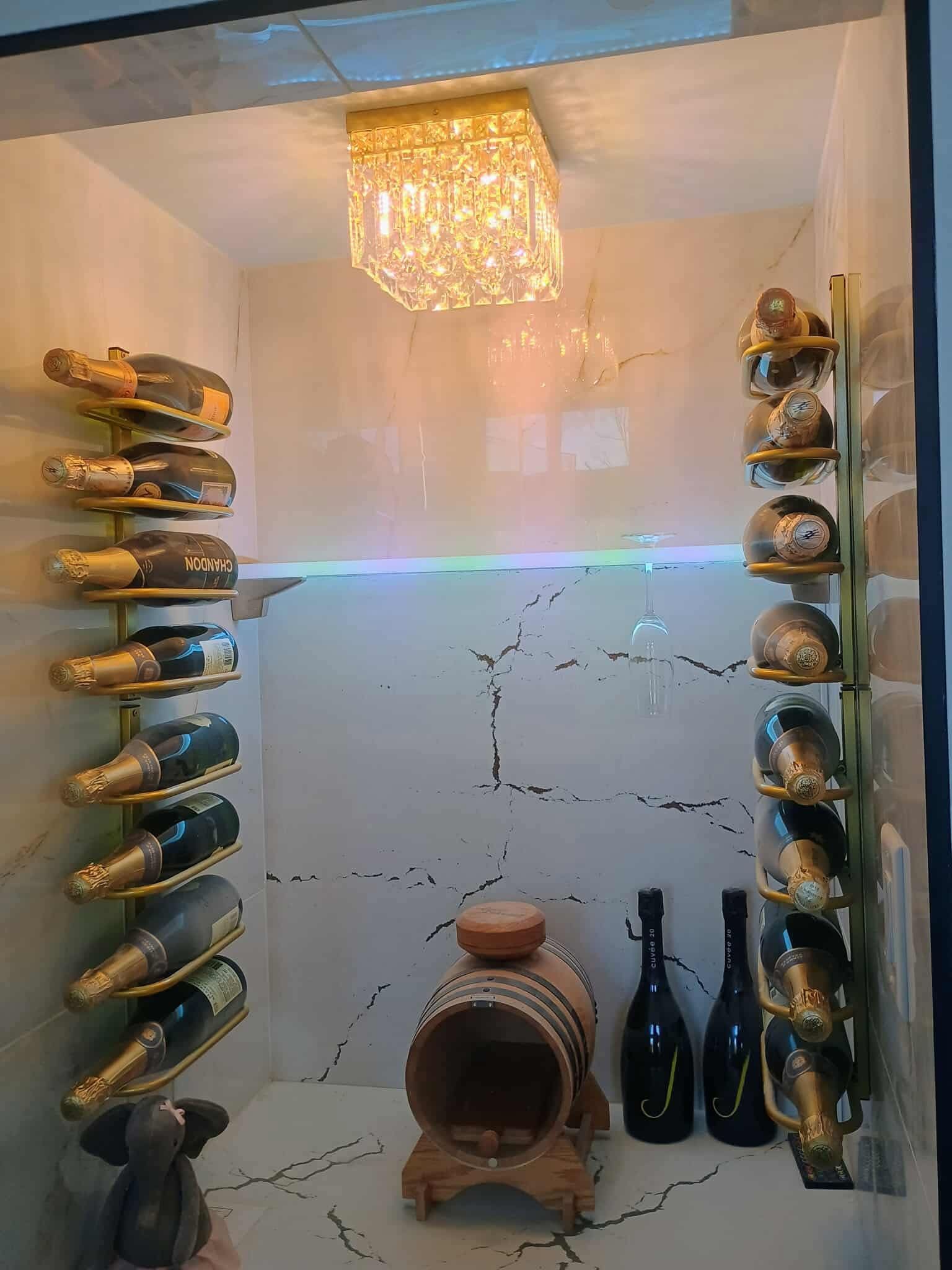 Wall-mounted wine racks in a cozy cellar with bottles, a hanging chandelier, and a clay amphora.