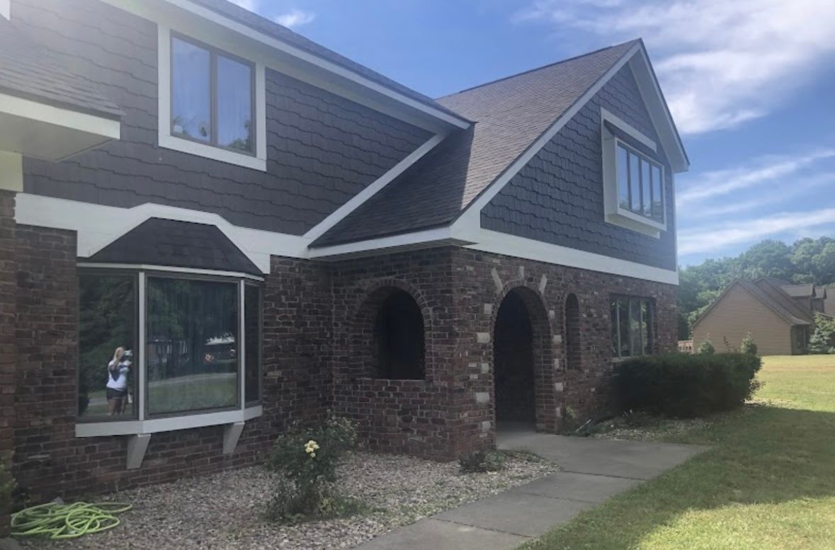 Brick house with arched porch, gray siding, and a small statue by the sliding glass door.