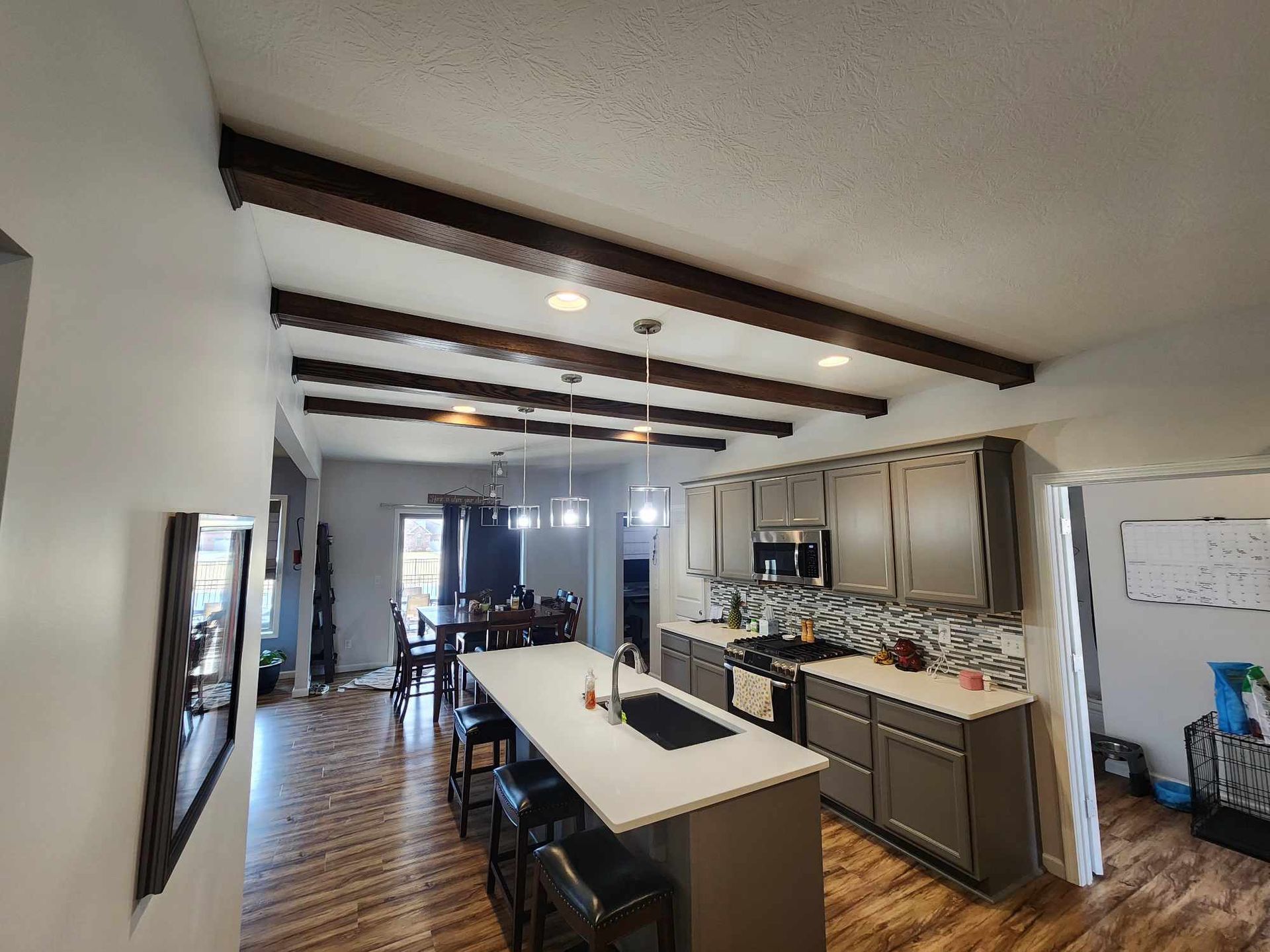 Open kitchen with island, wood beam ceiling, and dining area in a bright open-plan home