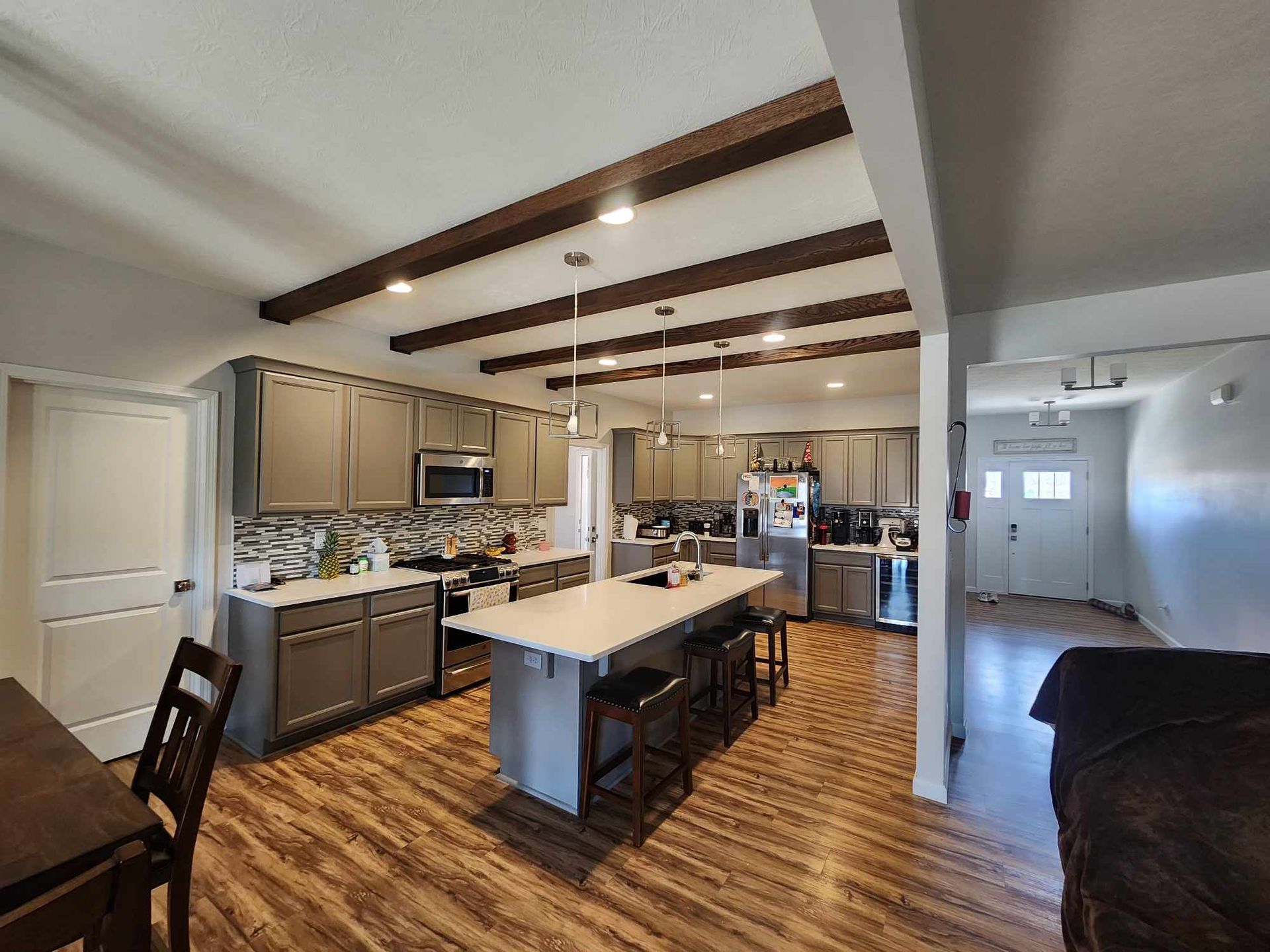Open-concept kitchen and dining area with island, wood beams, and hardwood floors