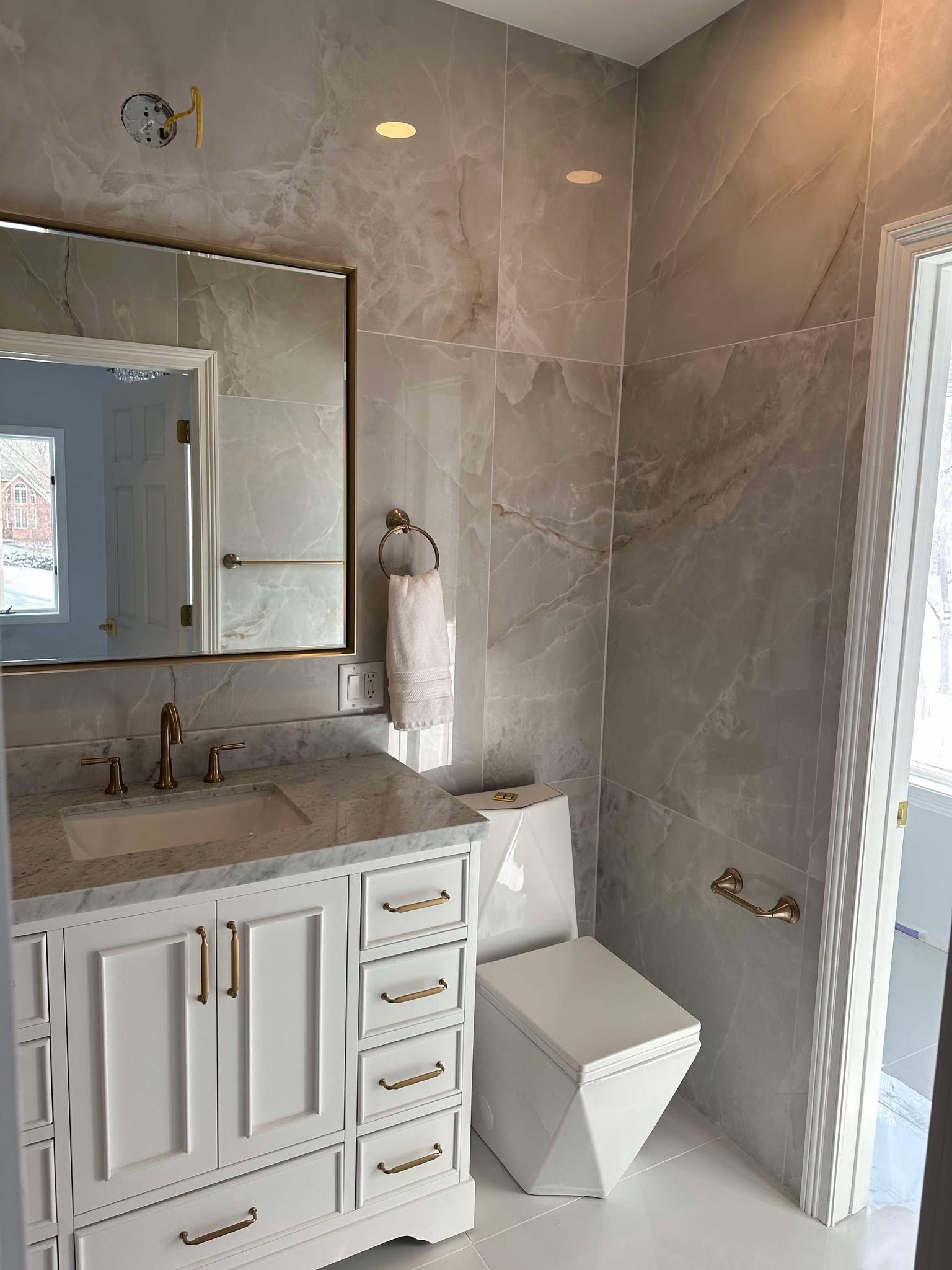 Modern bathroom with white vanity, marble countertop, mirror, and tiled shower.