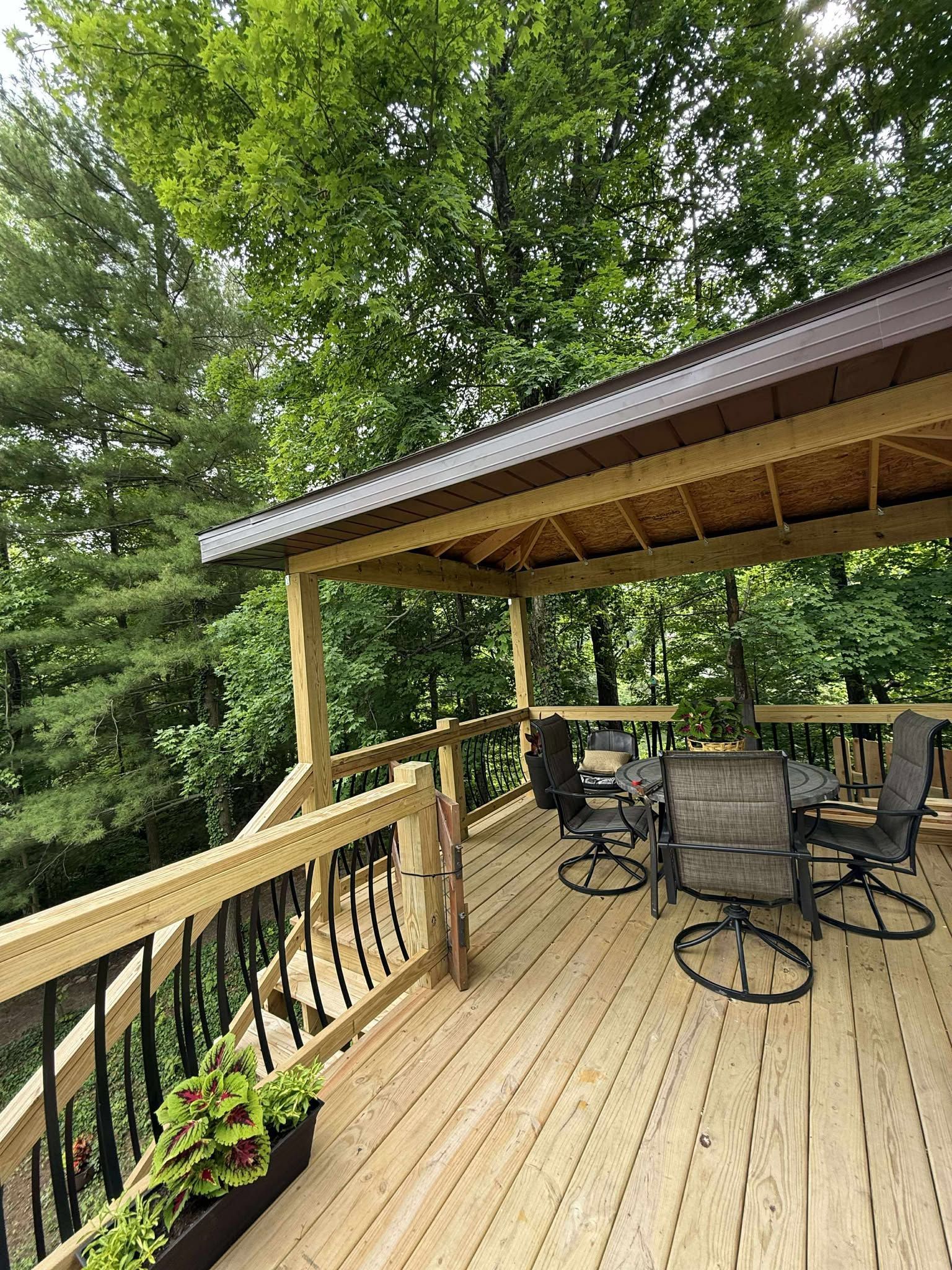 Wooden deck with patio furniture overlooking a lush green forest