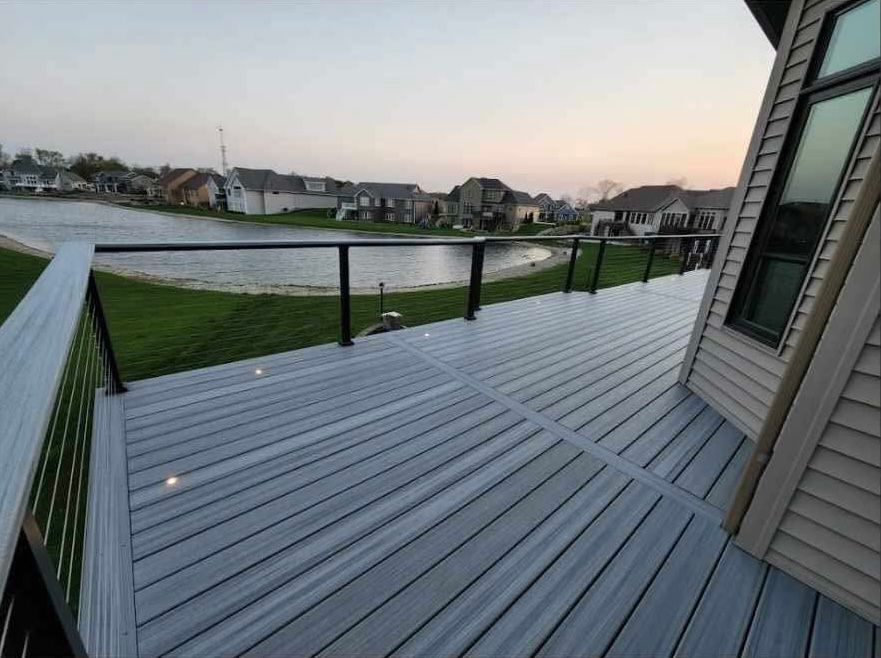 Empty gray deck overlooking a grassy waterfront neighborhood at dusk