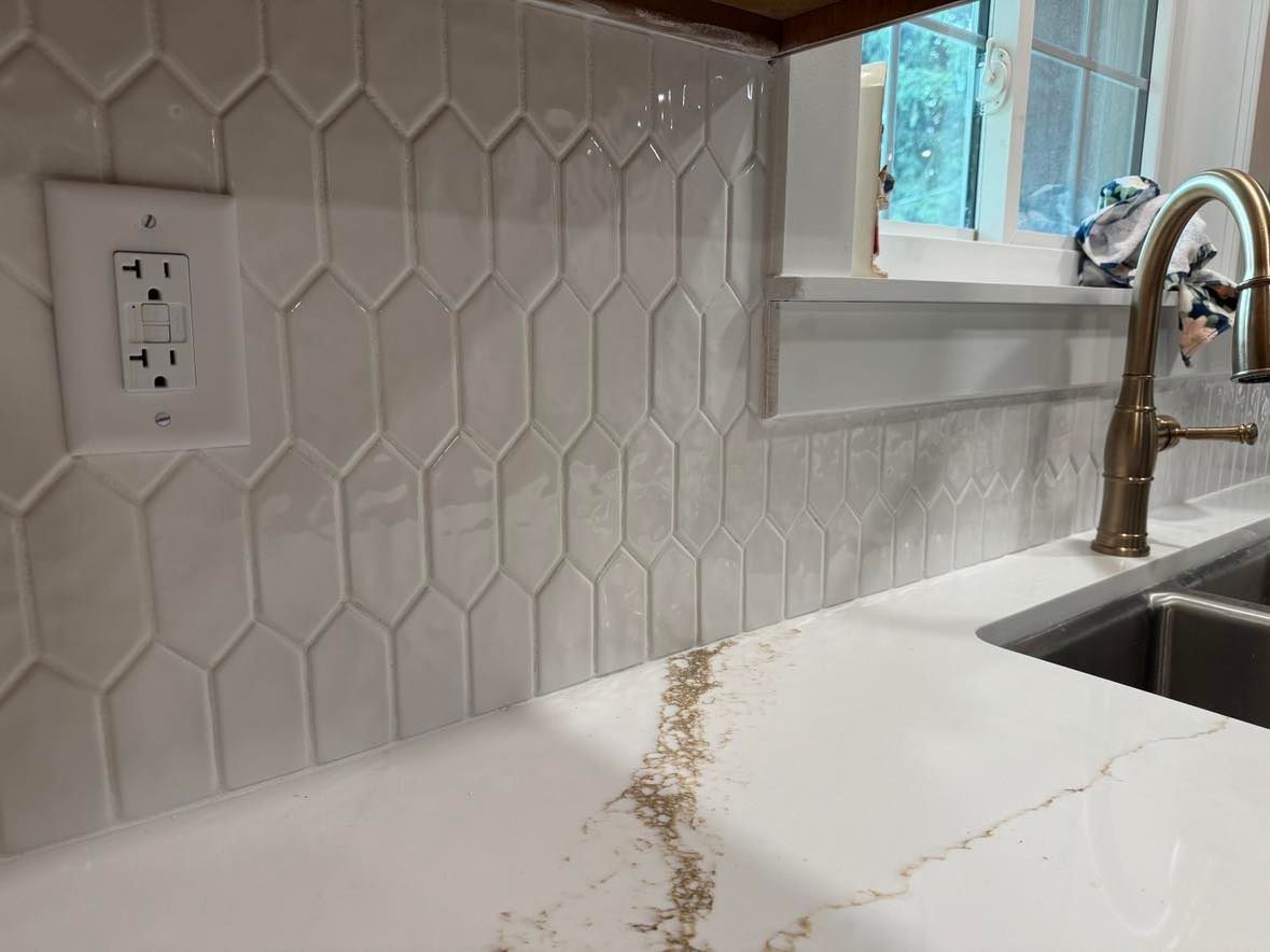 White kitchen counter with a long crack near a sink and hexagonal tile backsplash.