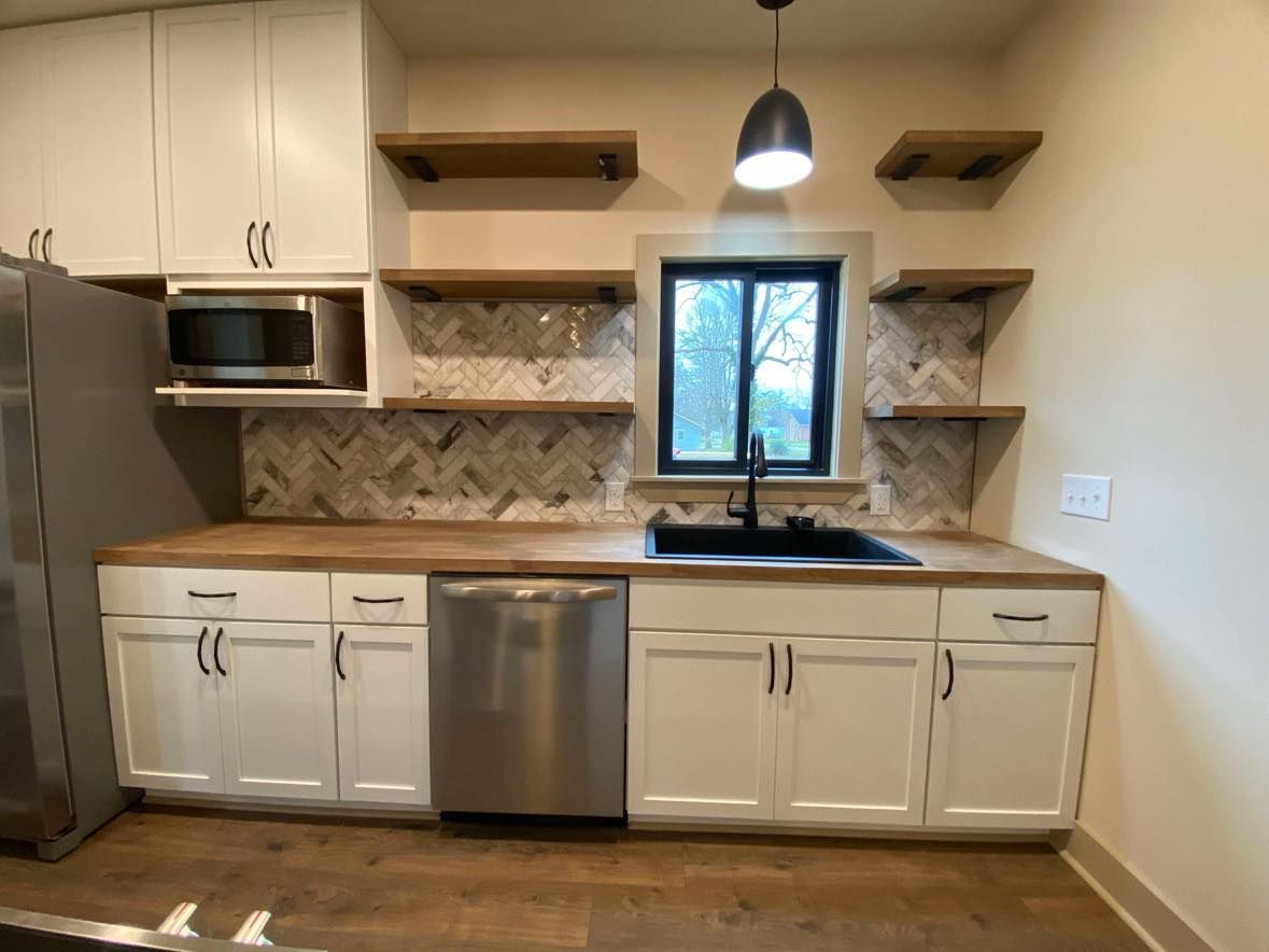 Modern kitchen with white cabinets, wood shelves, stainless appliances, and a window above the sink