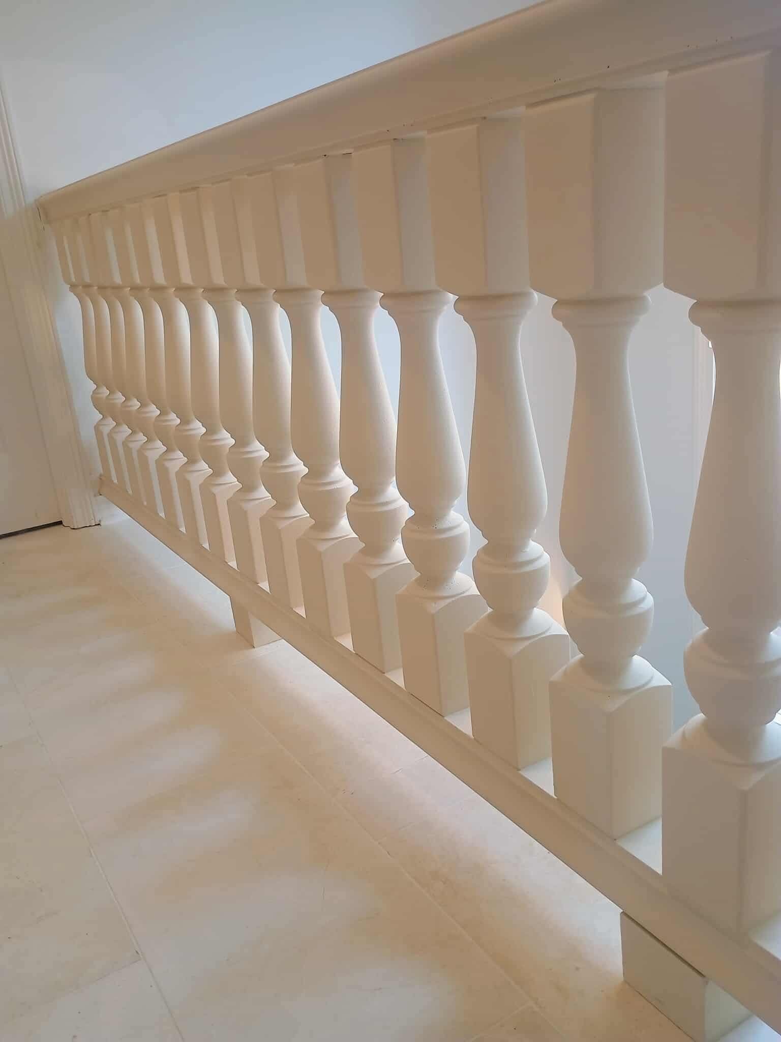 White staircase balustrade with decorative spindles along a bright hallway corner