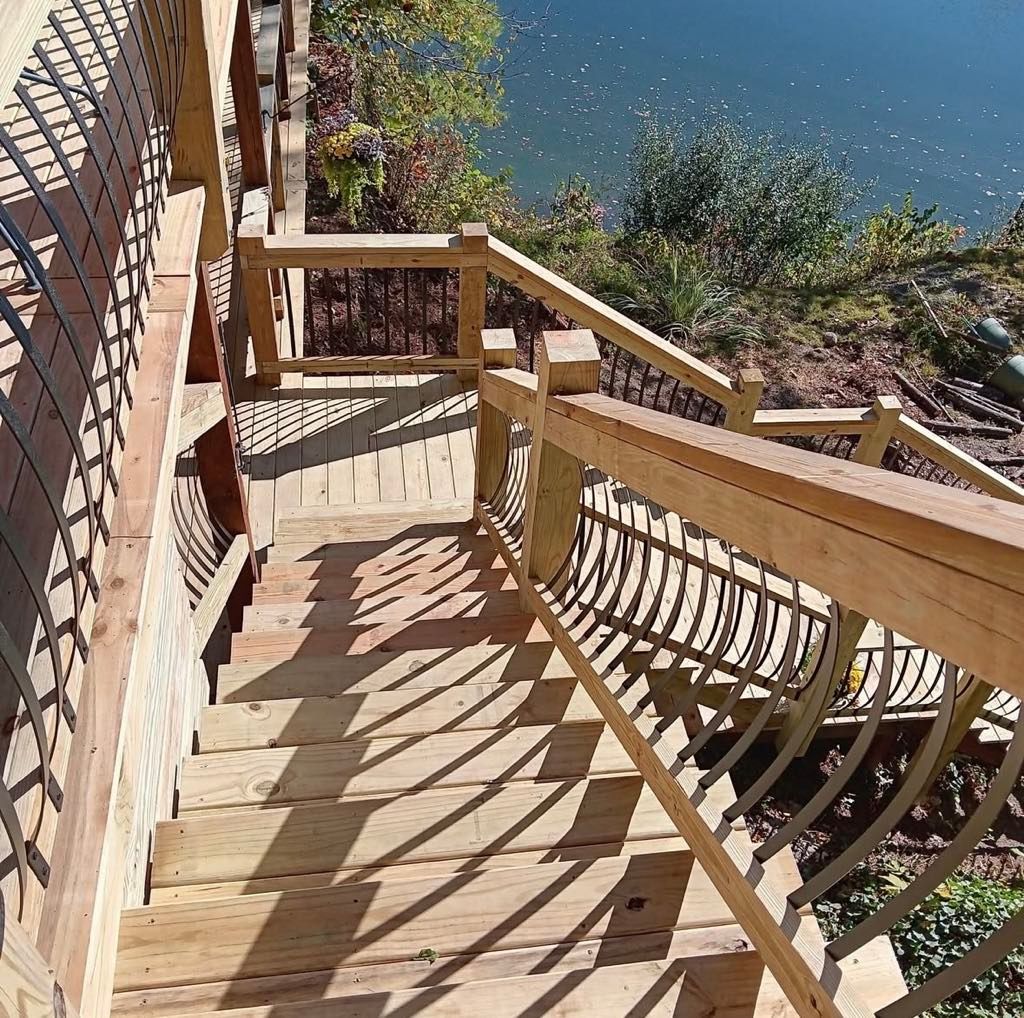 Wooden stairs with railings descending to a blue lake on a sunny day