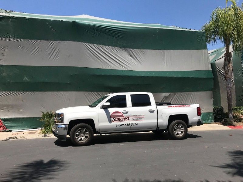A white truck is parked in front of a green and white building.