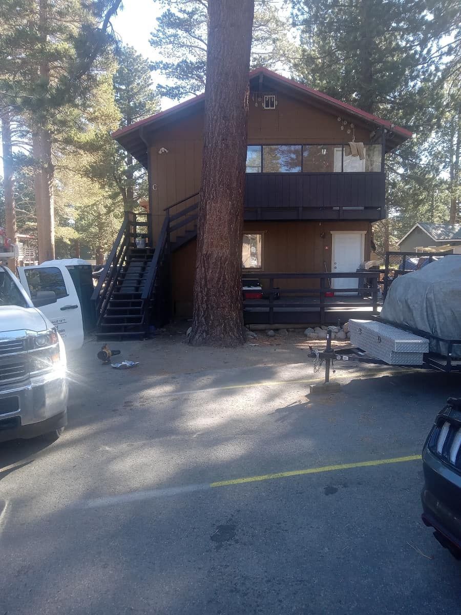 A house with stairs and a boat trailer parked in front of it.