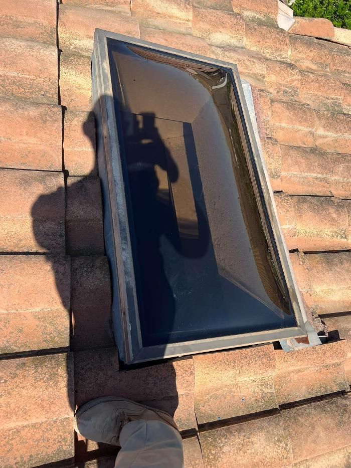 A skylight is sitting on top of a tiled roof.