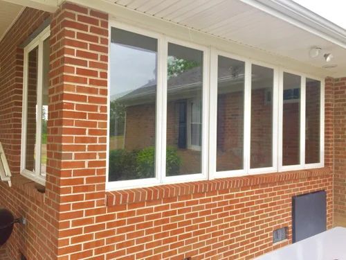 Brick house exterior with large white-framed windows and a covered porch