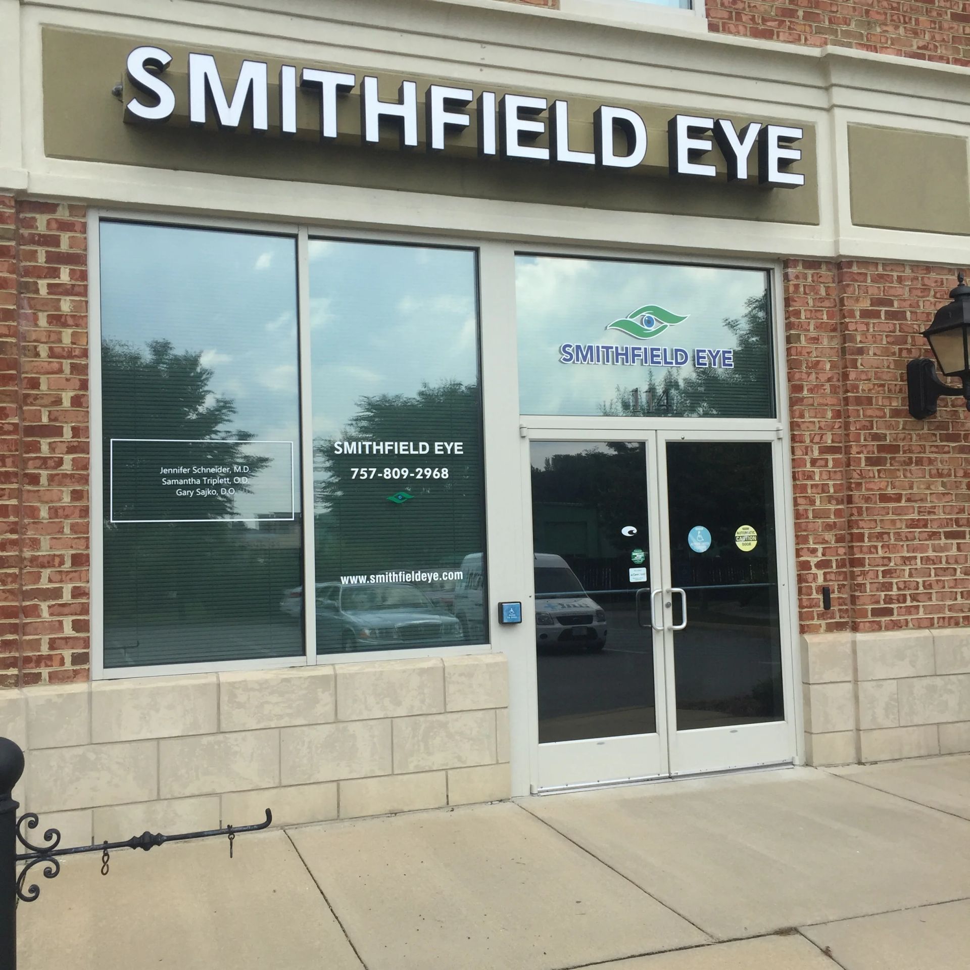 Storefront of Smithfield Eye with brick facade, glass doors, and windows on a sidewalk