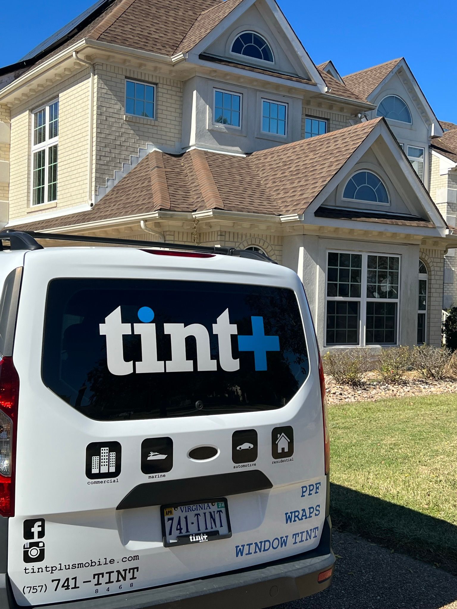 White Tint+ van parked in front of a beige house with a tiled roof and blue window shutters