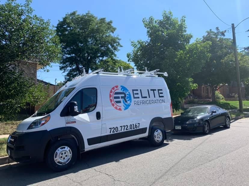 A white van is parked on the side of the road next to a black car.