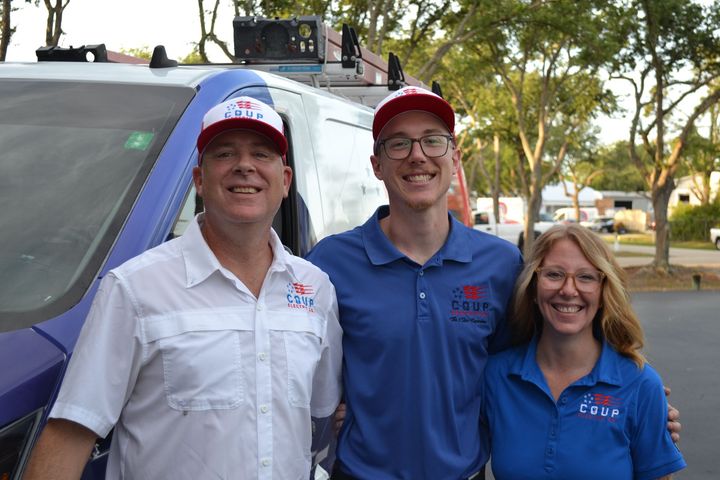 Three people are posing for a picture in front of a van.