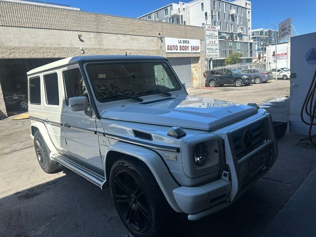 White Mercedes G-Class SUV parked outside a building on a sunny street.