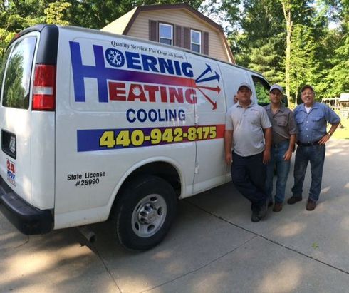 Three men standing in front of a heating and cooling van.