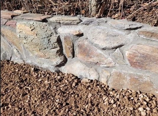 A stone wall with a pile of gravel next to it.
