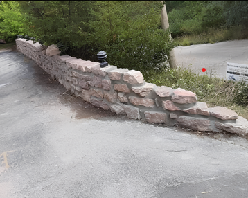 A stone wall is along the side of a road
