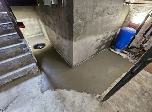 A concrete floor is being poured in a basement