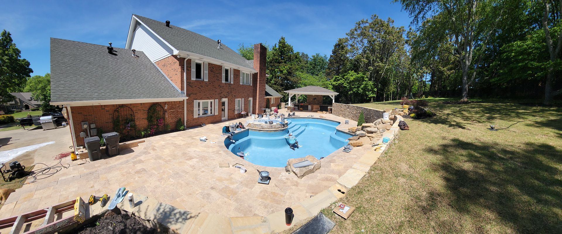 There is a large swimming pool in the backyard of a house.