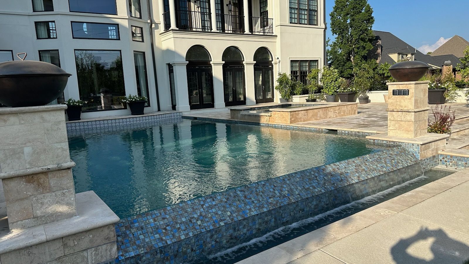 A large swimming pool in front of a large house.