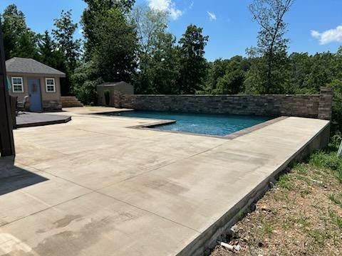 A large swimming pool is in the backyard of a house.