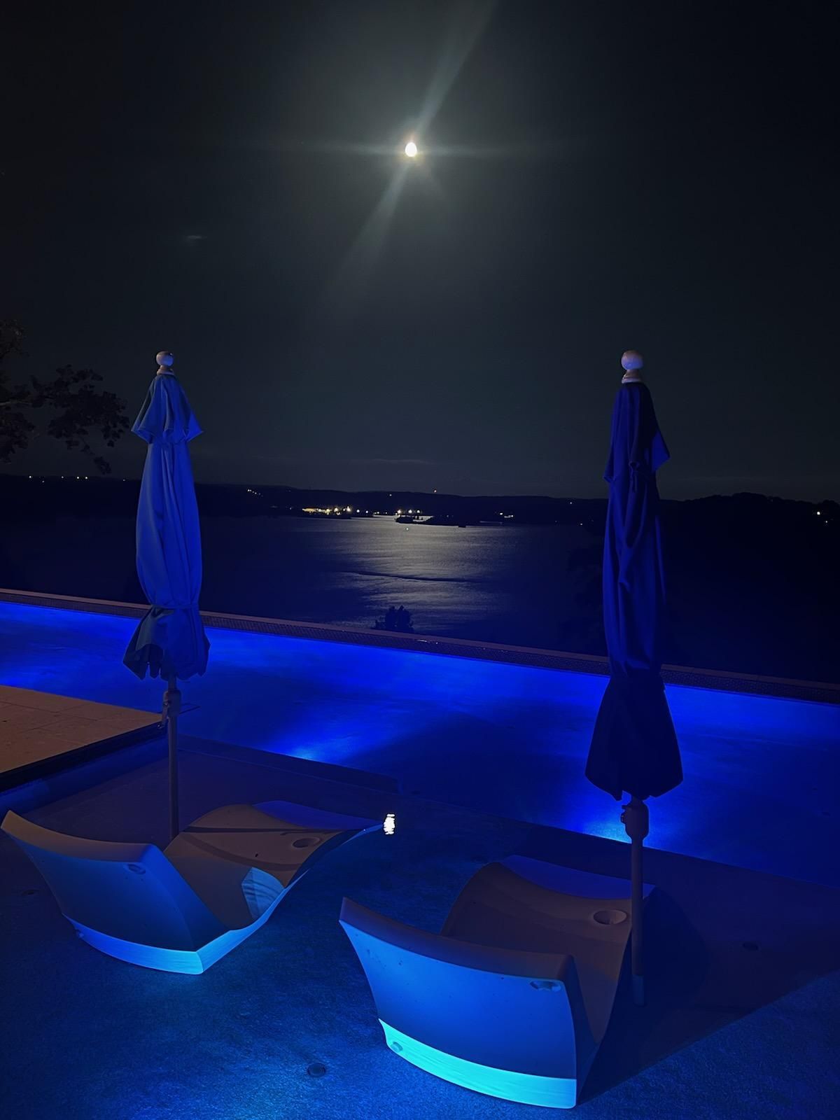 A swimming pool is lit up with blue lights at night