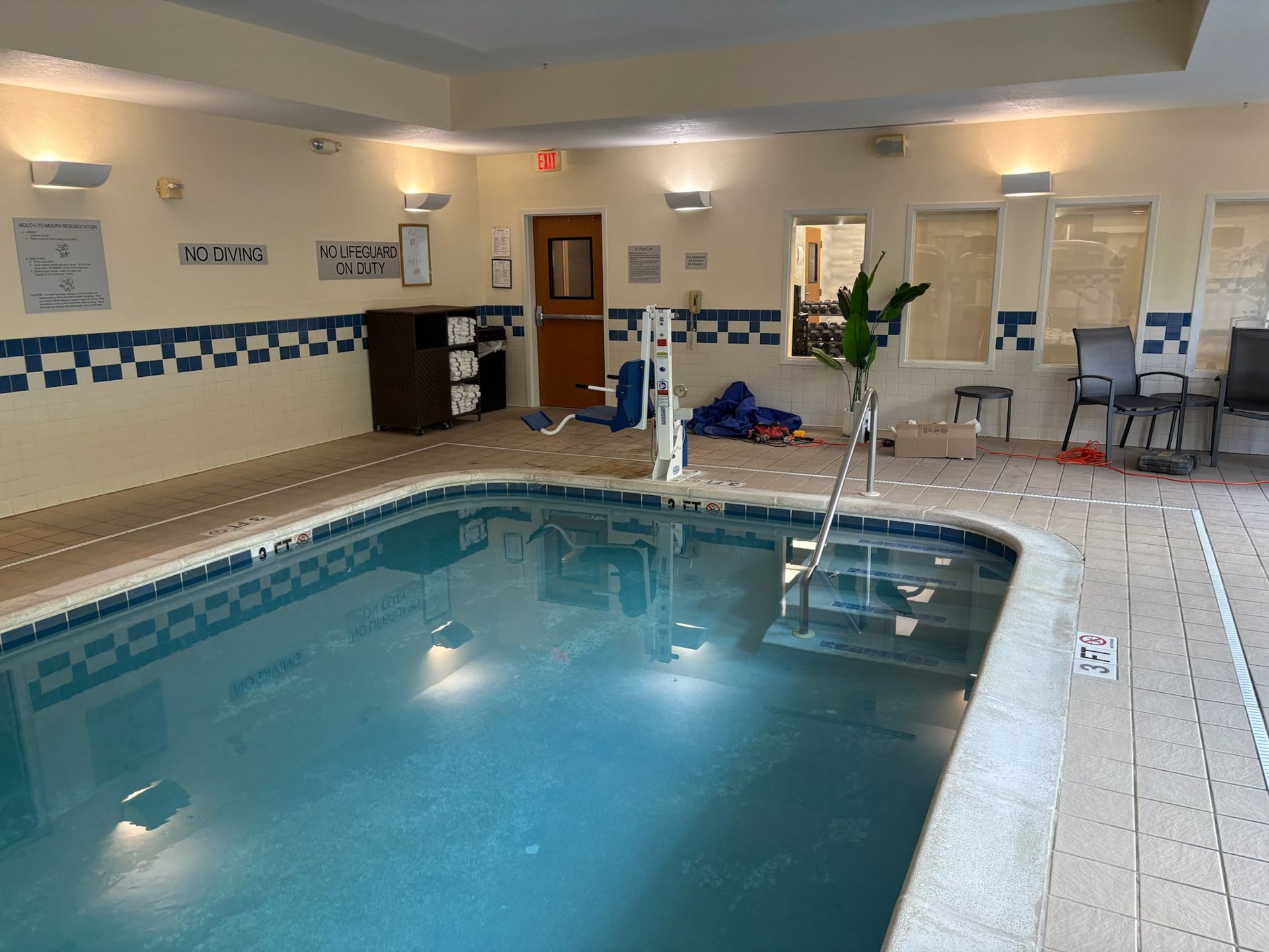 A large indoor swimming pool is surrounded by chairs and tables.