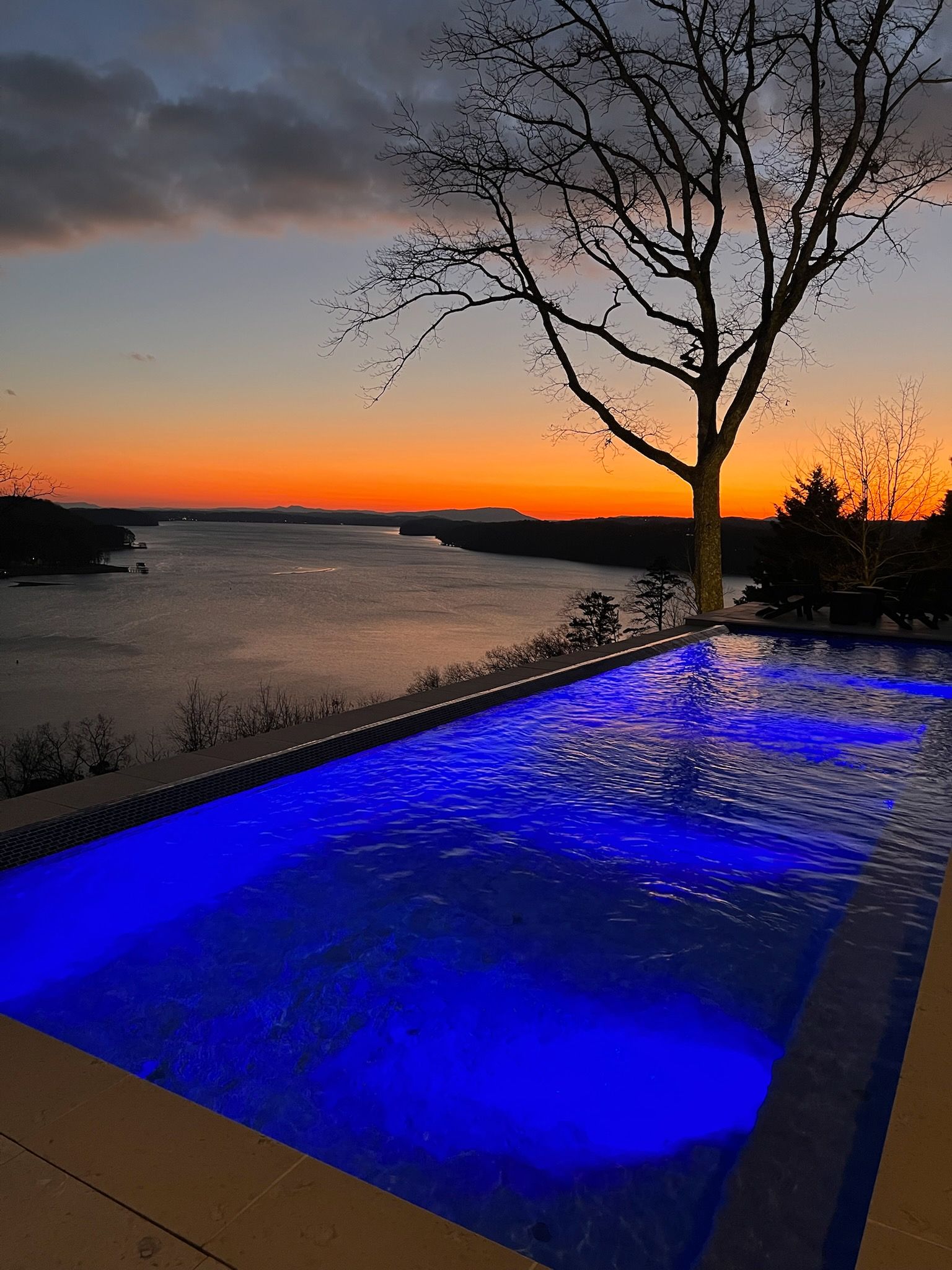 A swimming pool with a view of a river at sunset.