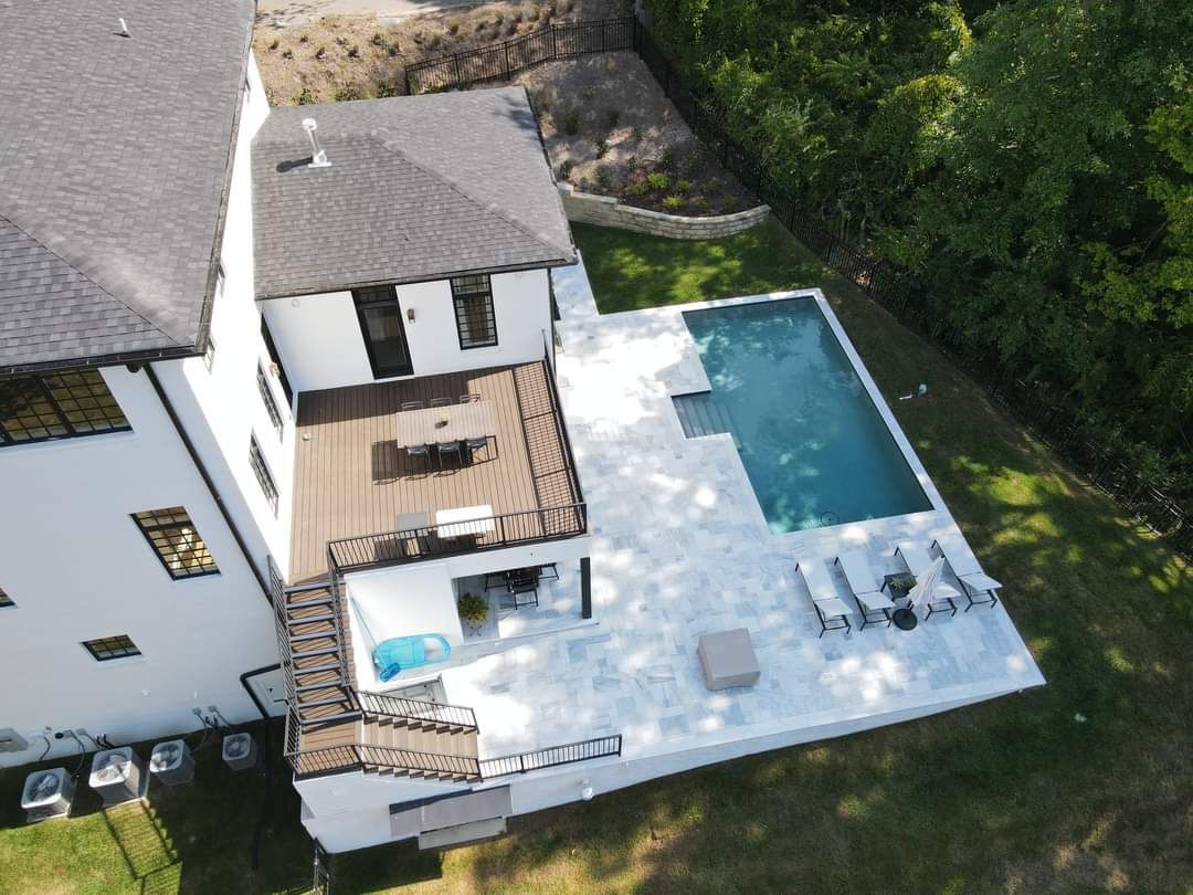 An aerial view of a house with a large swimming pool in the backyard.