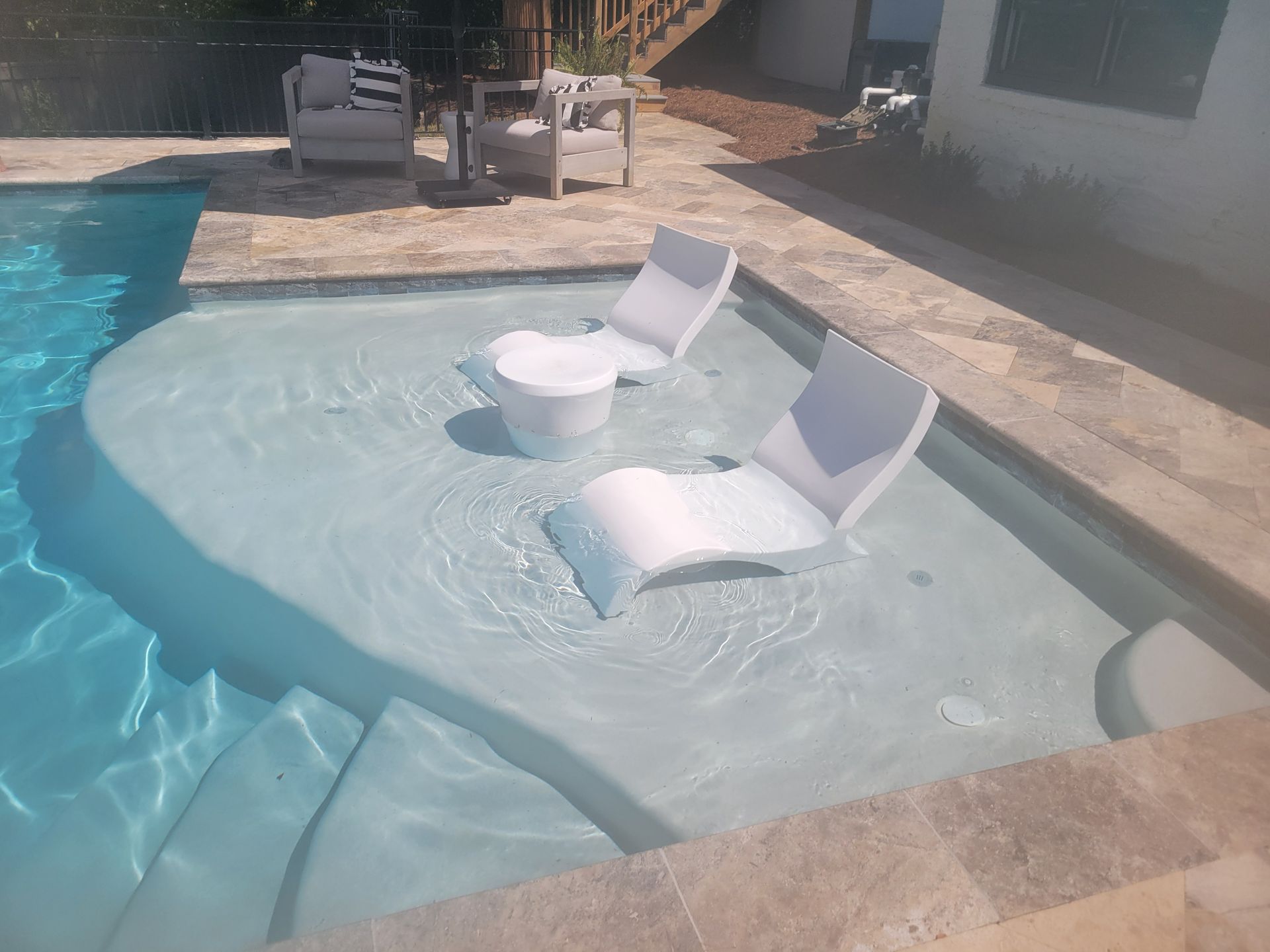 A swimming pool with chairs and a table in it.