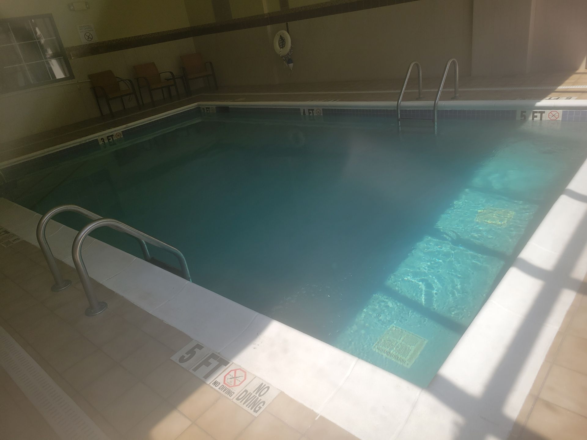 A large indoor swimming pool with stairs and a life preserver.