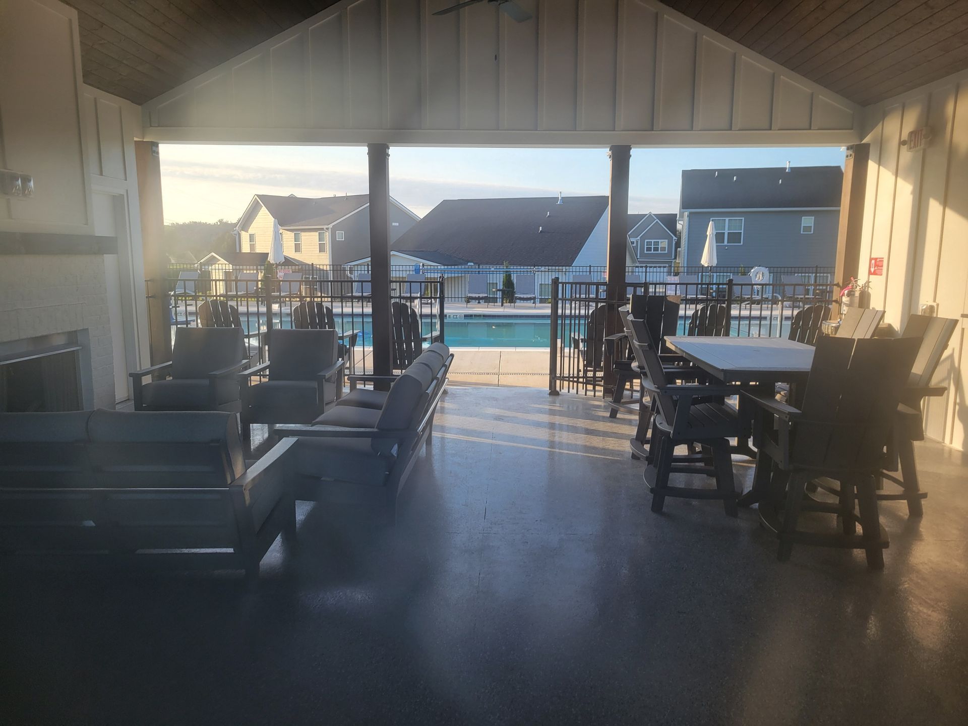 A covered patio with furniture and a pool in the background.
