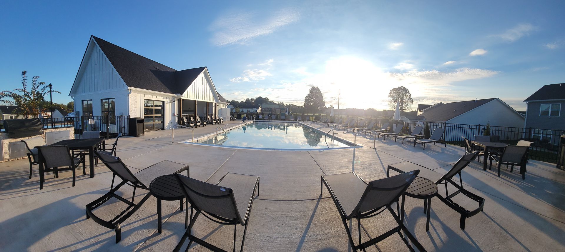 A large swimming pool with chairs and tables around it.
